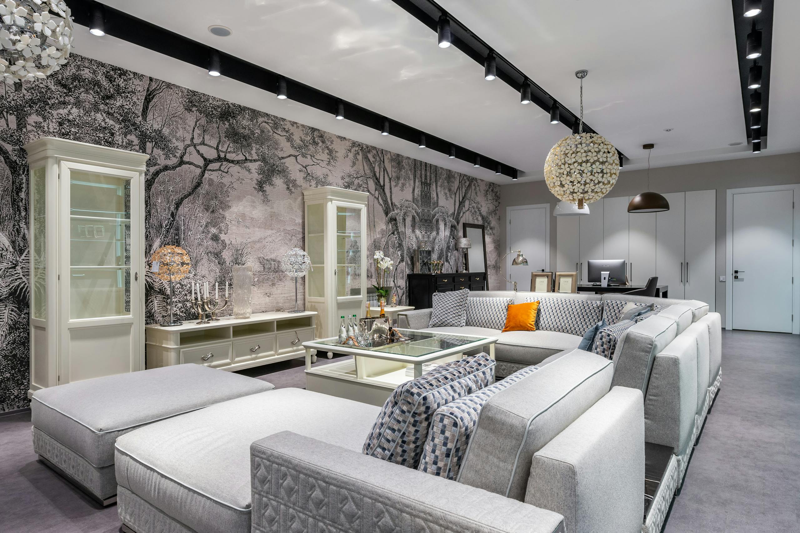 Comfortable sofa with cushions placed near table against wall with decorations on cabinet in spacious apartment with stylish design and doors