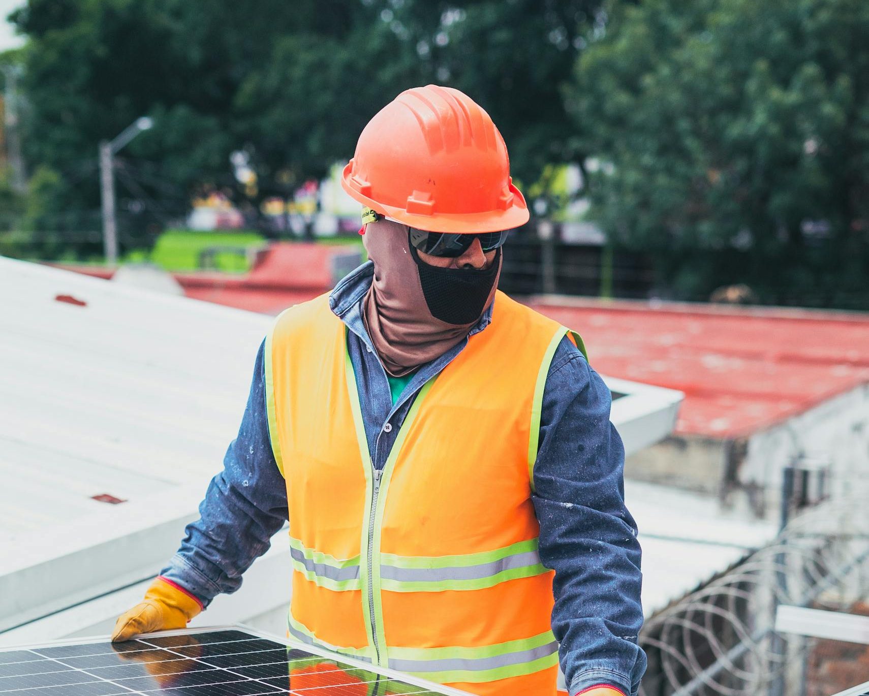 Technician in protective gear installing solar panels on a sunny day.